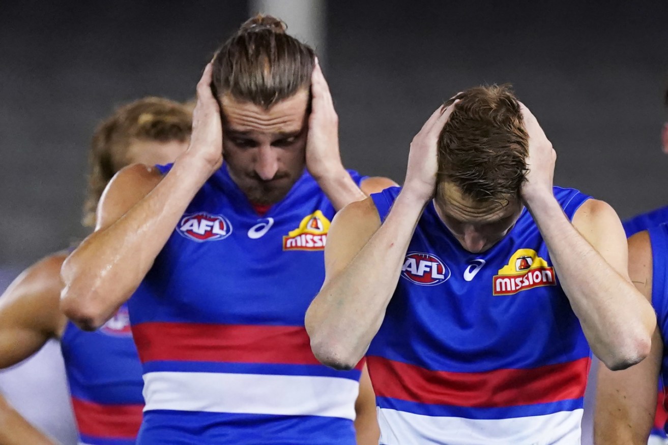 I can;' hear you: Western Bulldogs players come off the field after their loss  to Collingwood. 