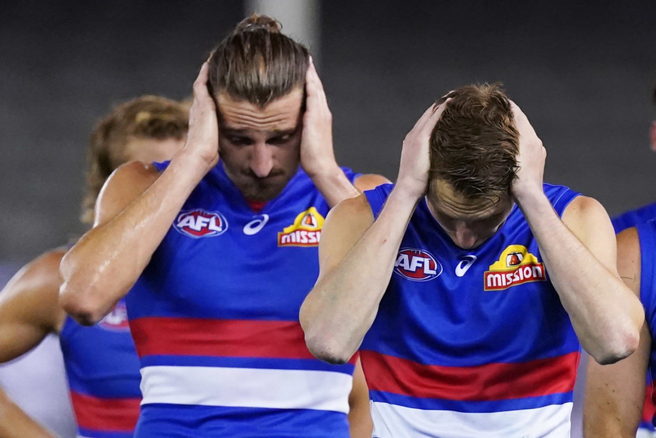 I can;' hear you: Western Bulldogs players come off the field after their loss to Collingwood.