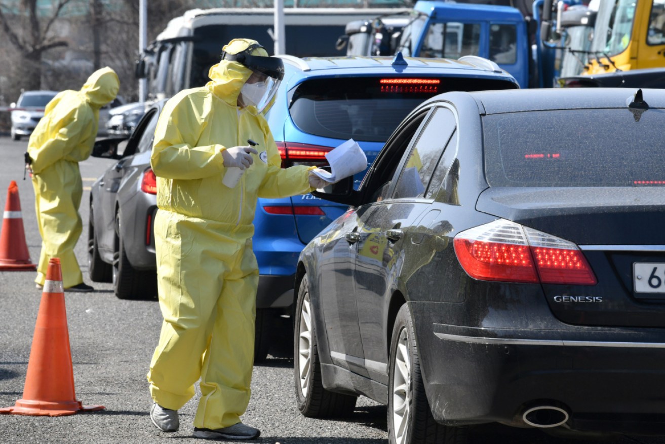 South Korean medical staff guide sick drivers to a drive-through virus test facility in Goyang, north of Seoul. 
