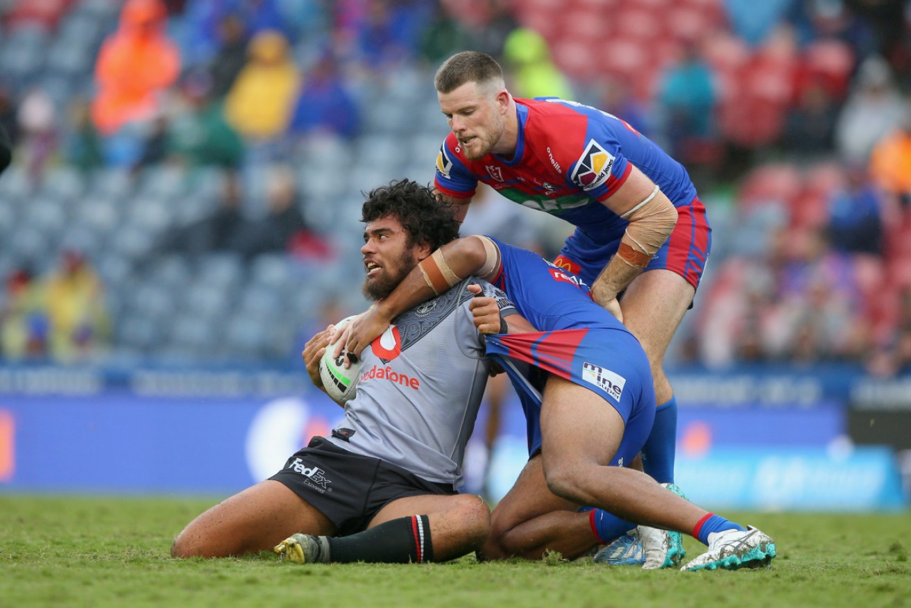In a bind: Isaiah Papali’i of the New Zealand Warriors is tackled by the Knights defence on Saturday. 