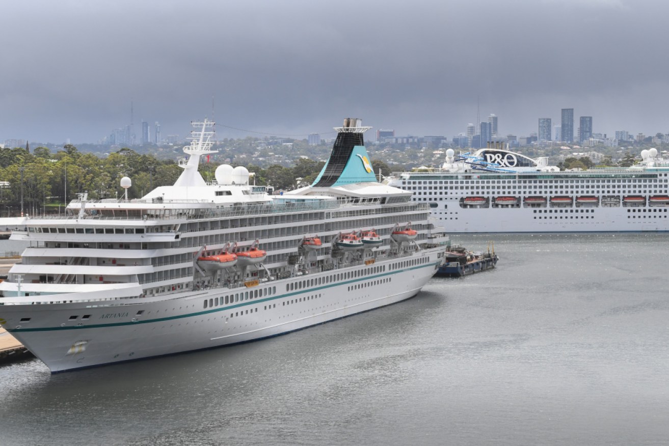 The Artania (front) in Sydney on March 16. It is now anchored off WA with confirmed COVID-19 cases on board.