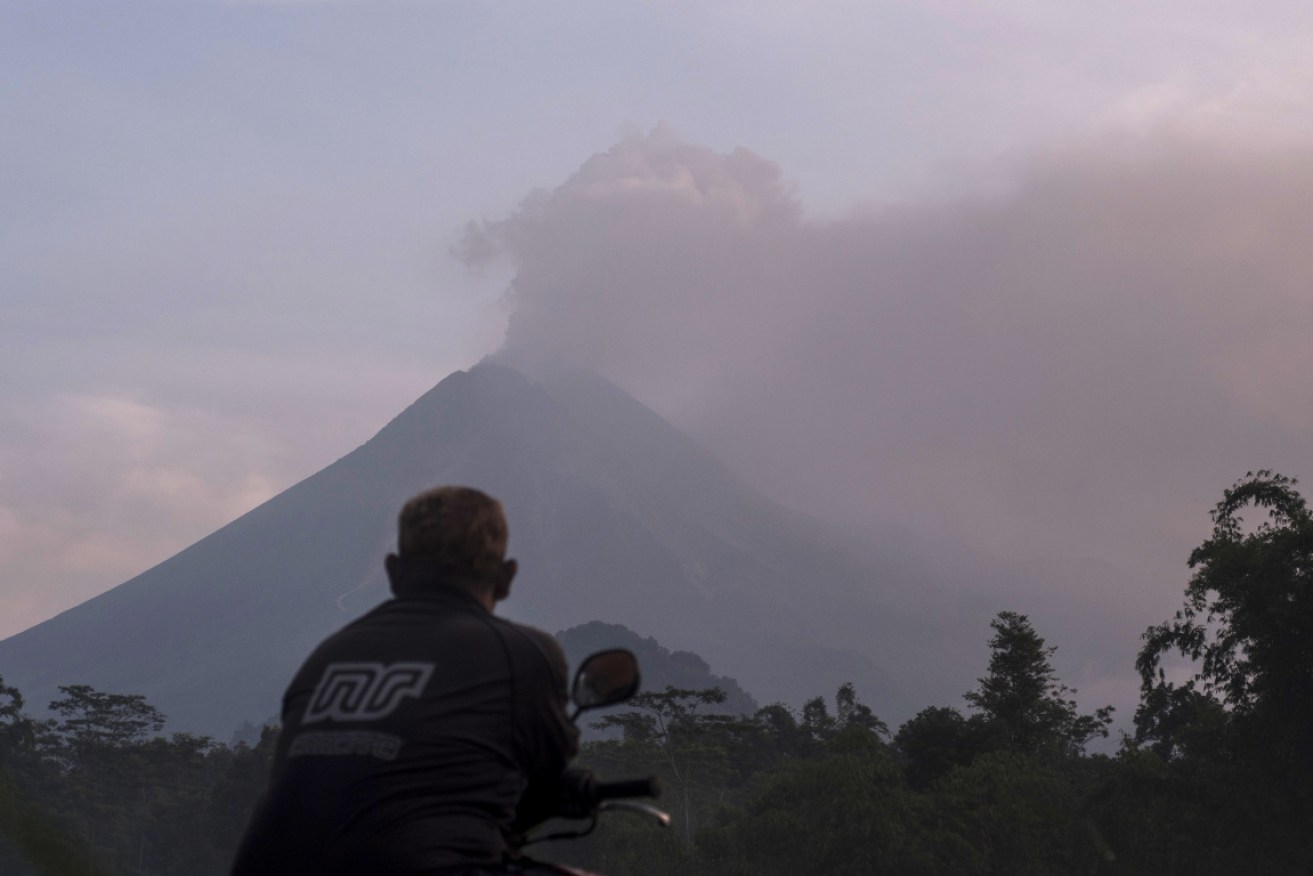 A man watches as Mount Merapi spews volcanic material into the air at Sleman on Tuesday.