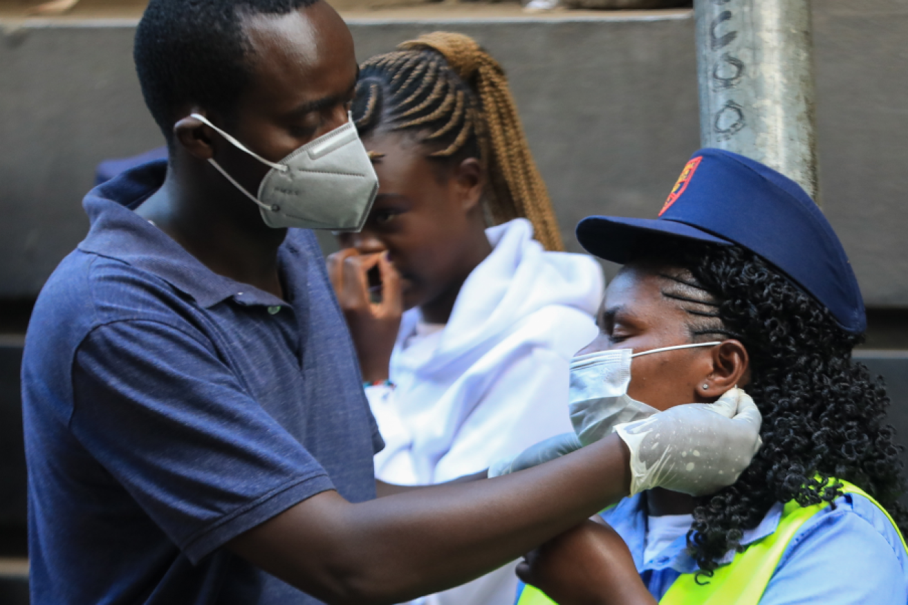 Nairobi bus drivers check each other's surgical masks, now part of their official uniform.