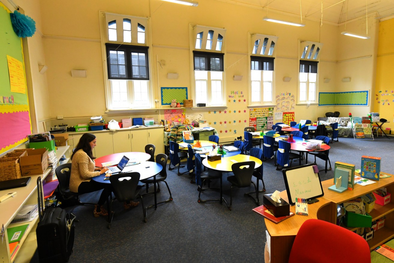 A teacher works in an empty classroom at a Melbourne primary school on Monday after the state brought forward holidays.