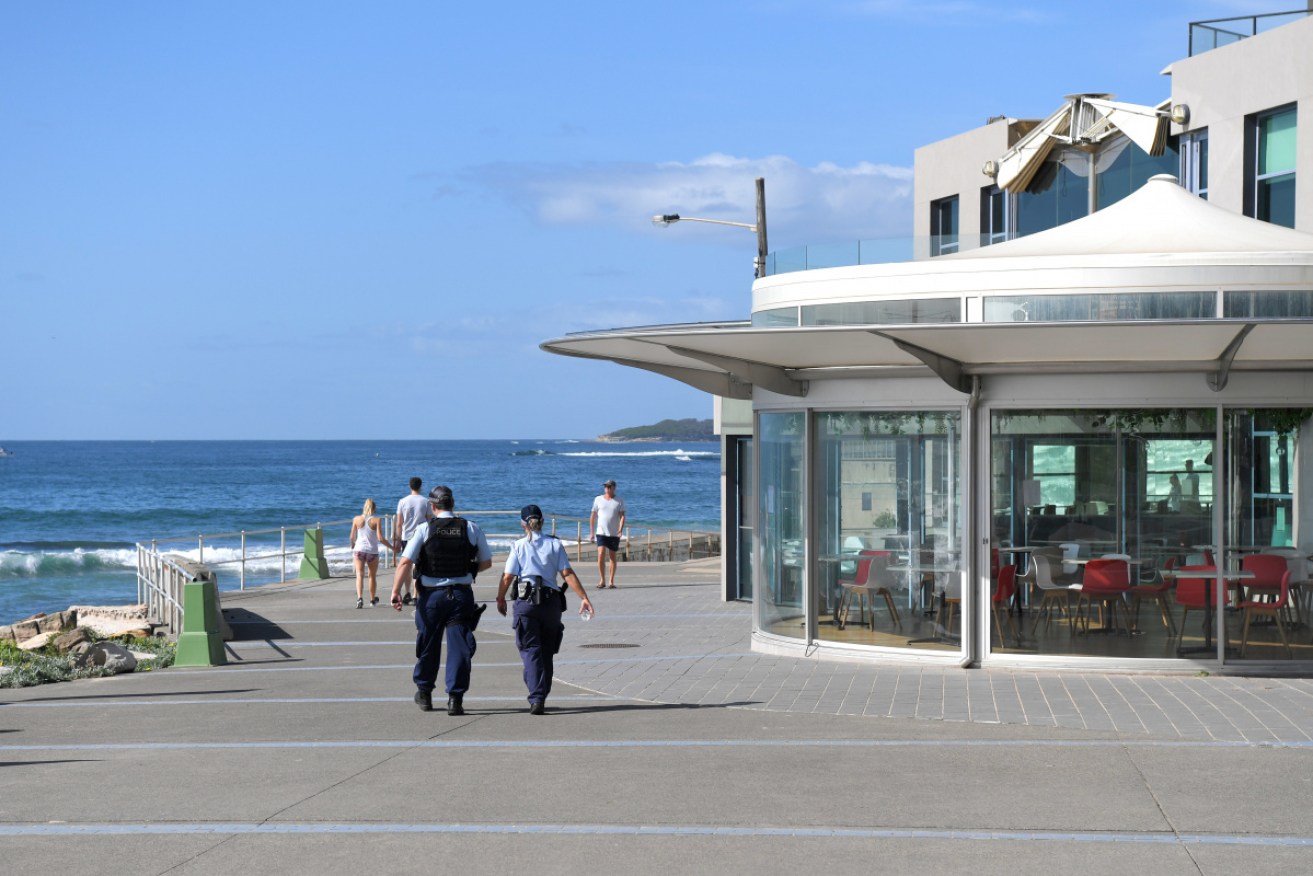 Police patrol Cronulla Beach, in Sydney's south, as tougher coronavirus restrictions are introduced.