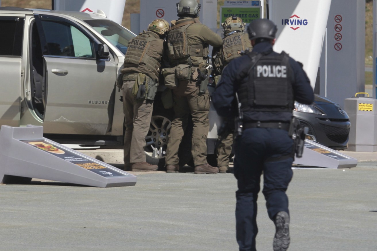 Royal Canadian Mounted Police officers take a suspect, allegedly driving a police pursuit car, into custody at a gas station in Nova Scotia.