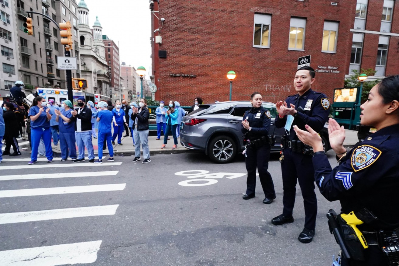 NYPD officers applaud the efforts of health workers in New York on Sunday.
