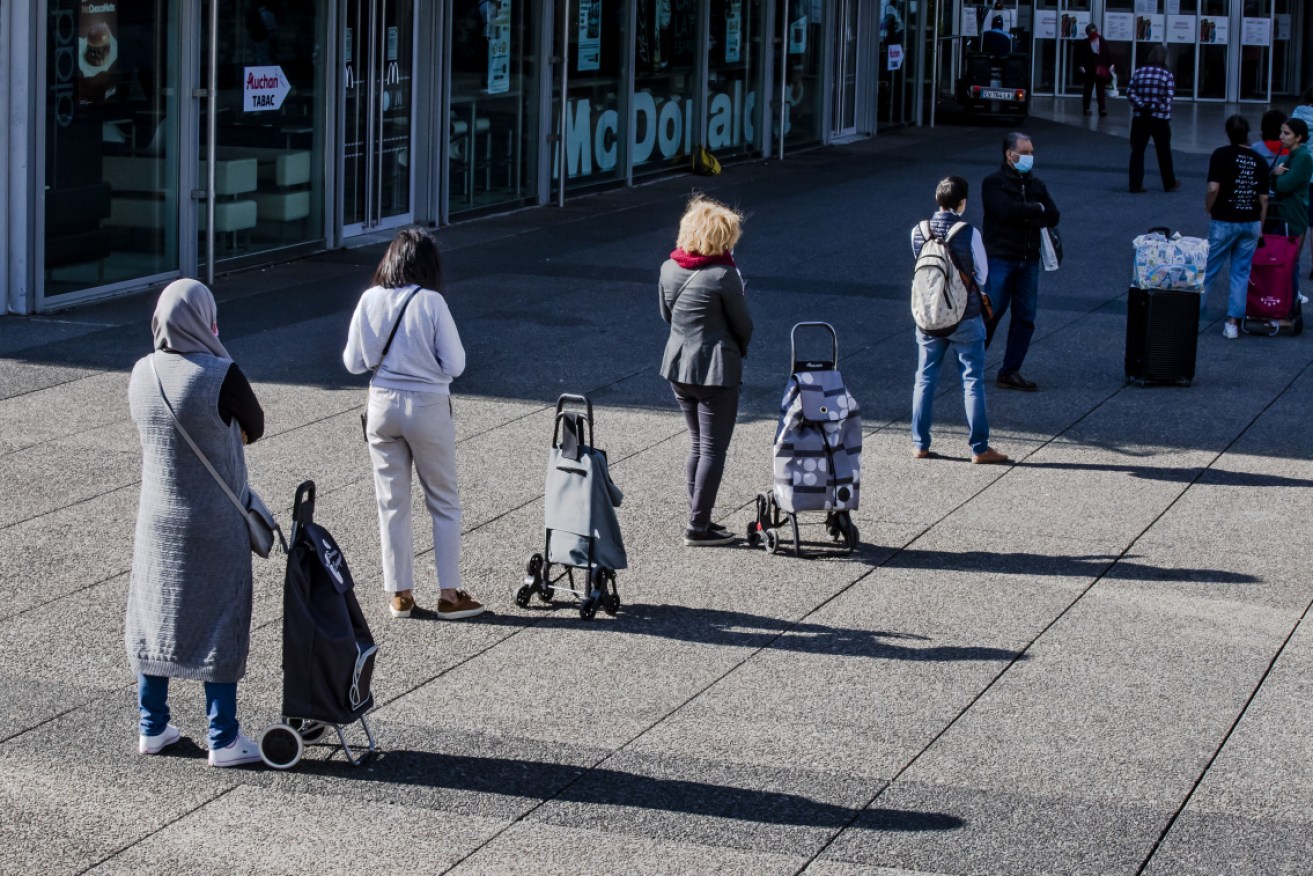 Shoppers queue in front of a grocery store to buy food in the La Defense business district in Paris on Monday.