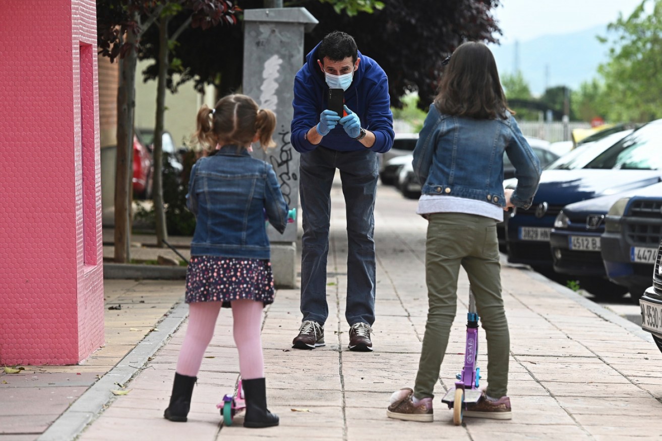 A man photographs his daughters at Alcala de Henares on the first day kids have been allowed outside since March 14. 

