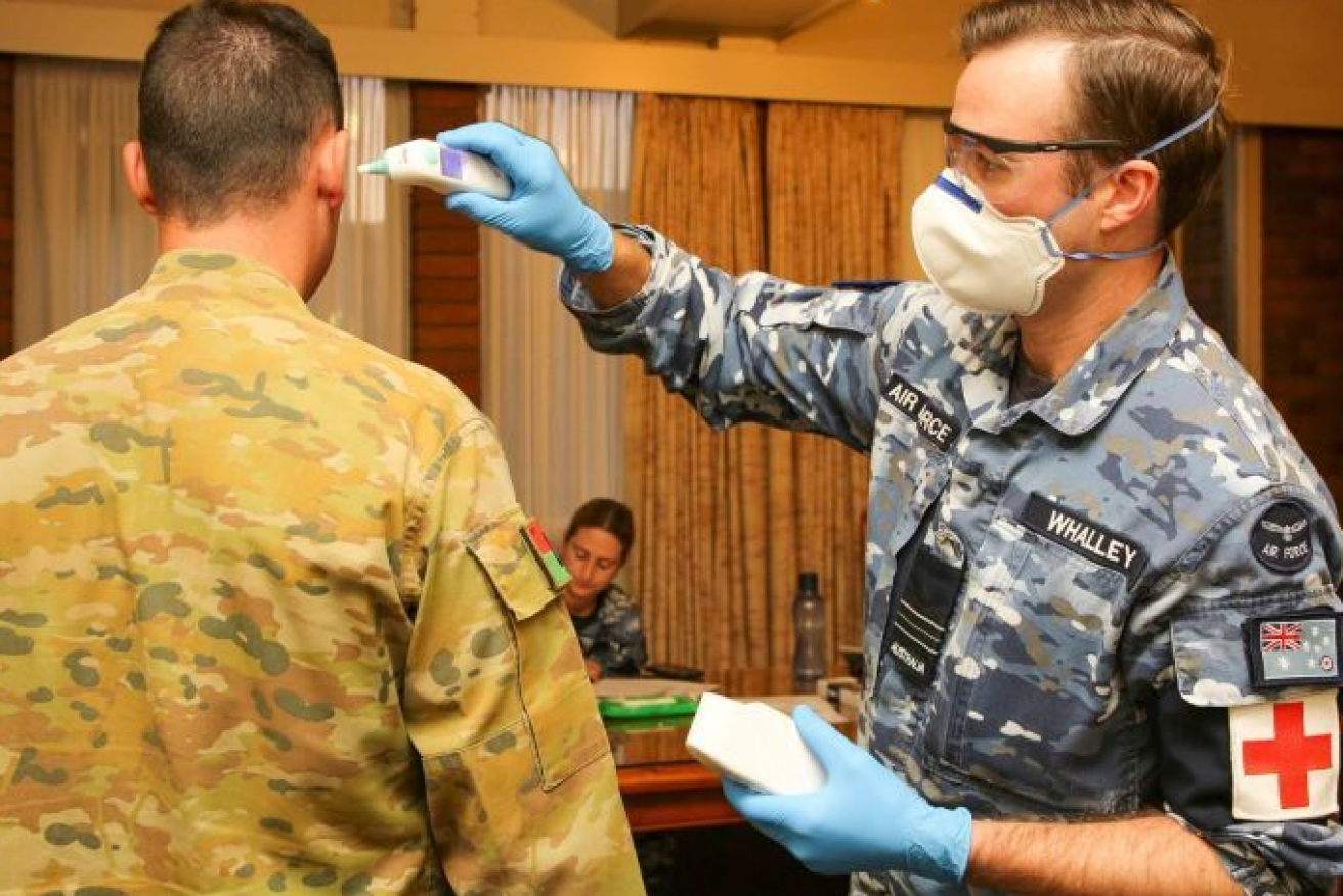 RAAF Squadron Leader Benedict Whalley (right) conducts a routine daily temperature check in hard-hit Burnie.