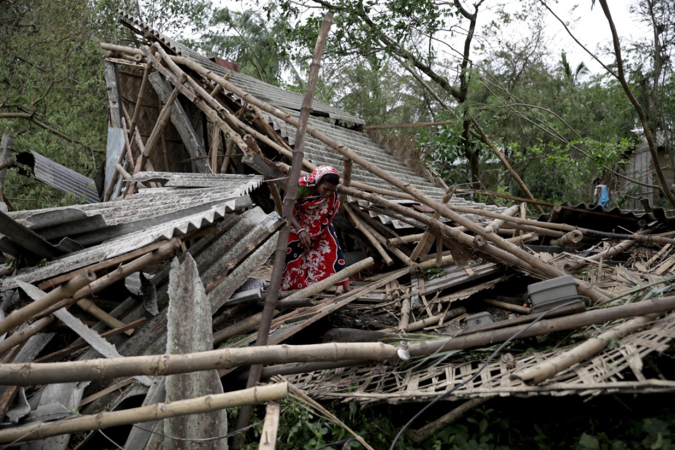Family members stand among the debris of their destroyed home in Bokkhali village near the Bay of Bengal, India.