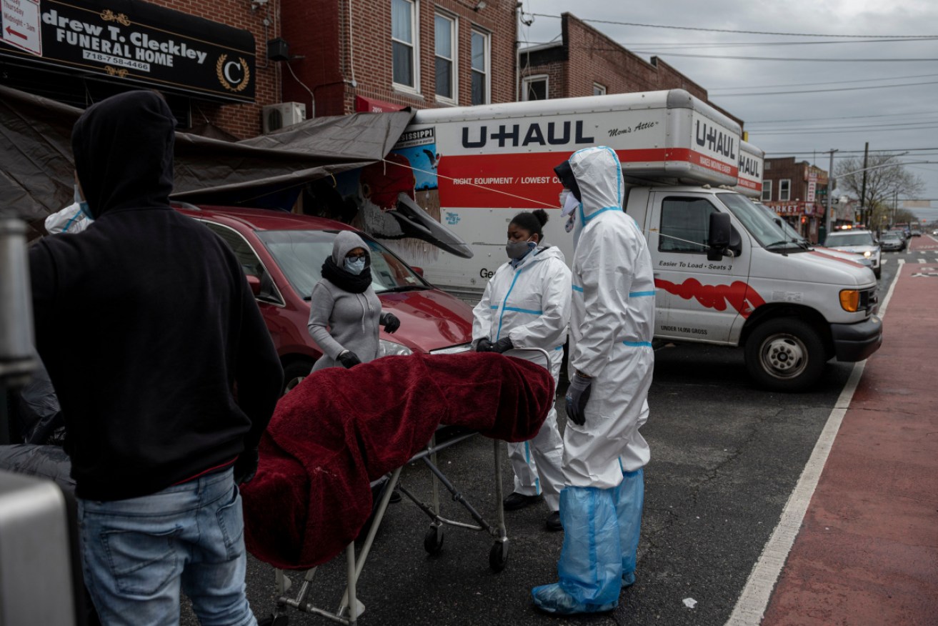 Workers in protective clothing transport one of the bodies outside the funeral home.