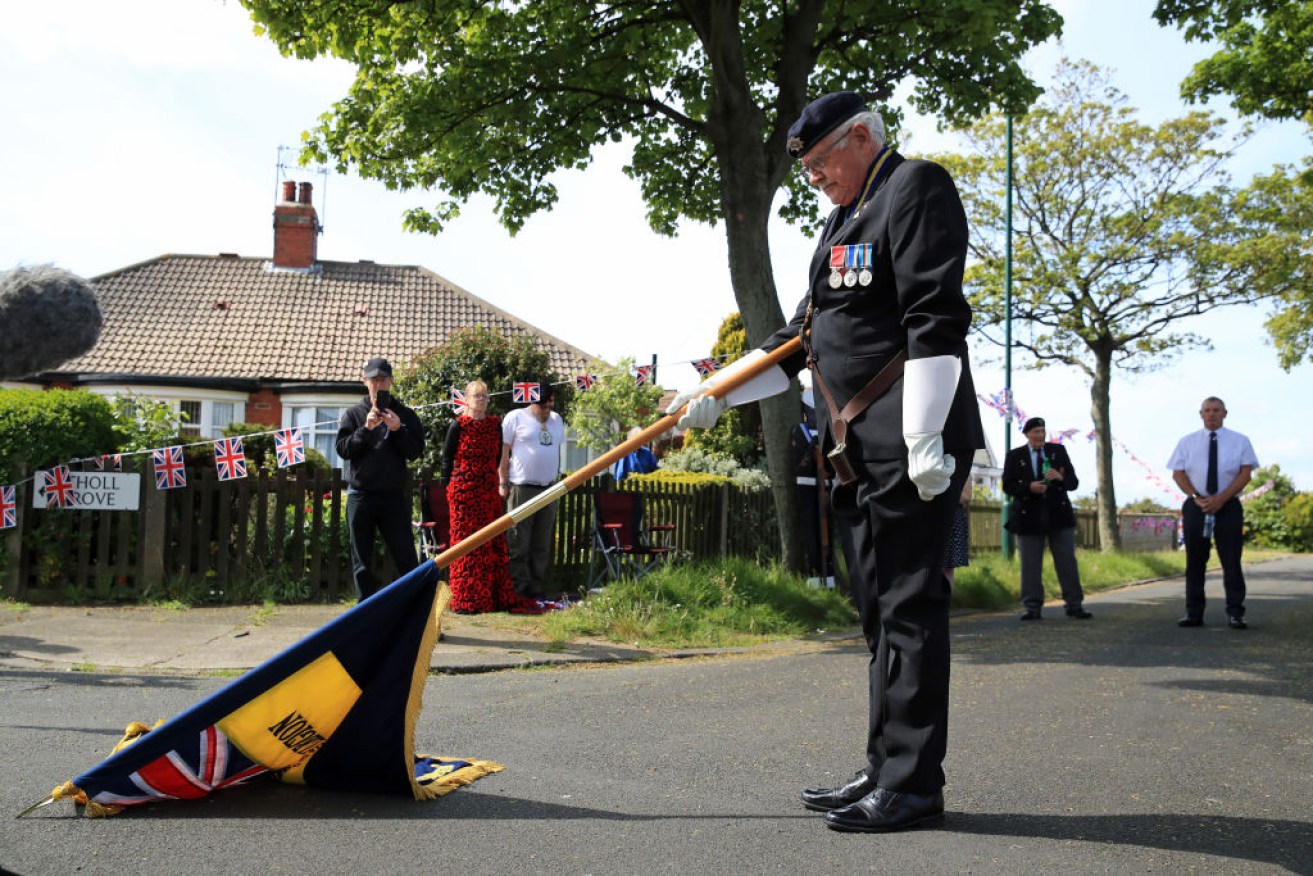 A Royal British Legion standard bearer marks two minutes silence in his neighbourhood on the 75th anniversary of VE Day.