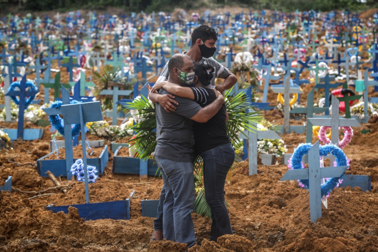 Relatives mourn a deceased relative during a mass burial of coronavirus victims.