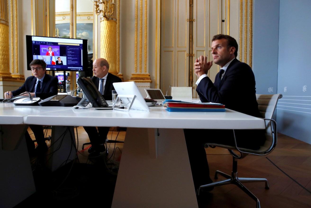 French President Emmanuel Macron (R) attends the international videoconference on vaccination with Foreign Affairs Minister Jean-Yves Le Drian (C) in Paris.