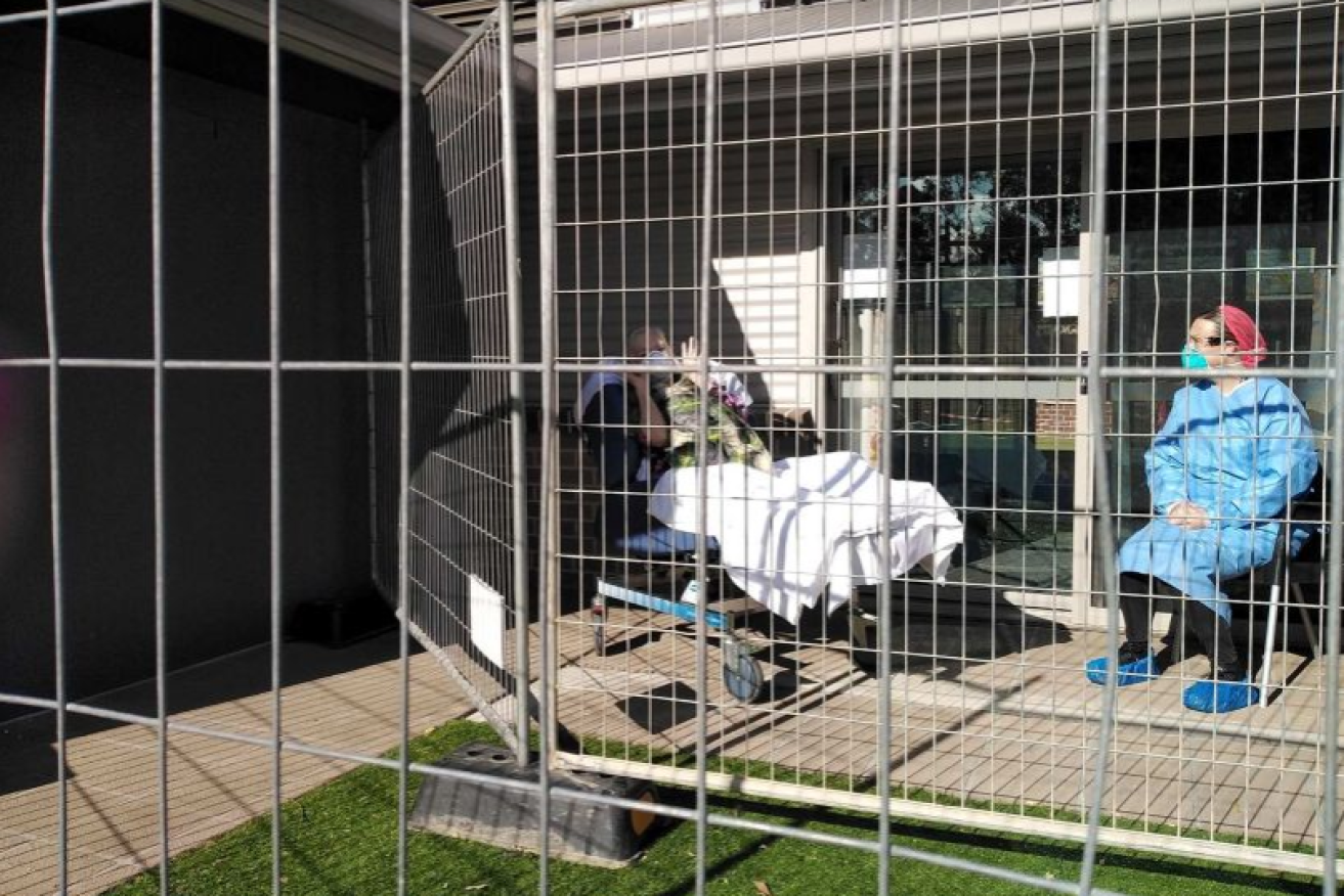 Bedridden Rose Davies takes the sun behind wire barriers at Newmarch House, where 14 senior residents have died.