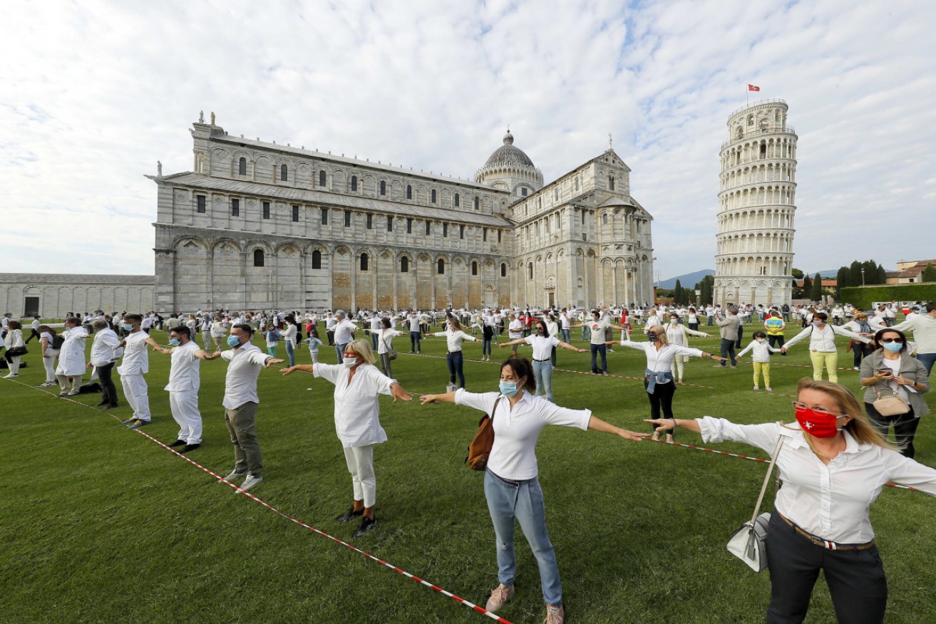 People gather for a flash mob on the Miracle's square in Pisa, Italy to celebrate the reopening of the Leaning Tower after it closed.