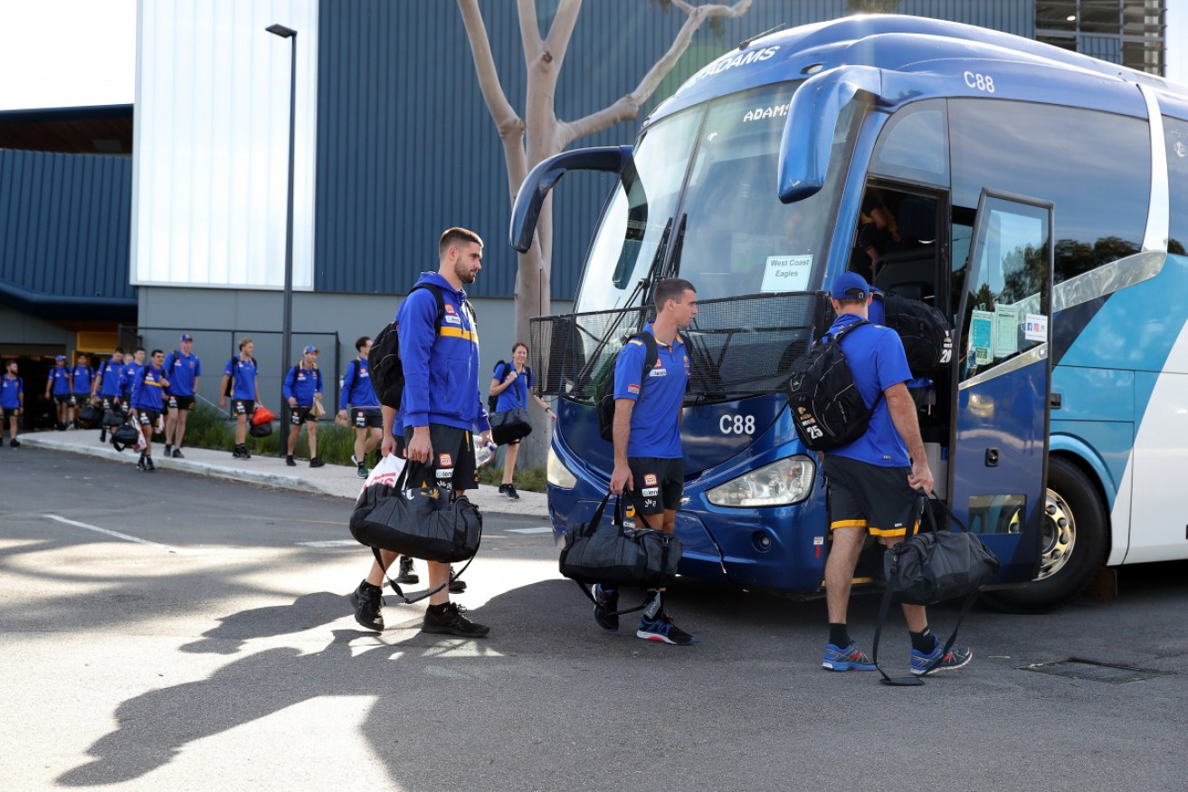 West Coast Eagles players practise social distancing as they board a bus on their way to their Queensland hub.
