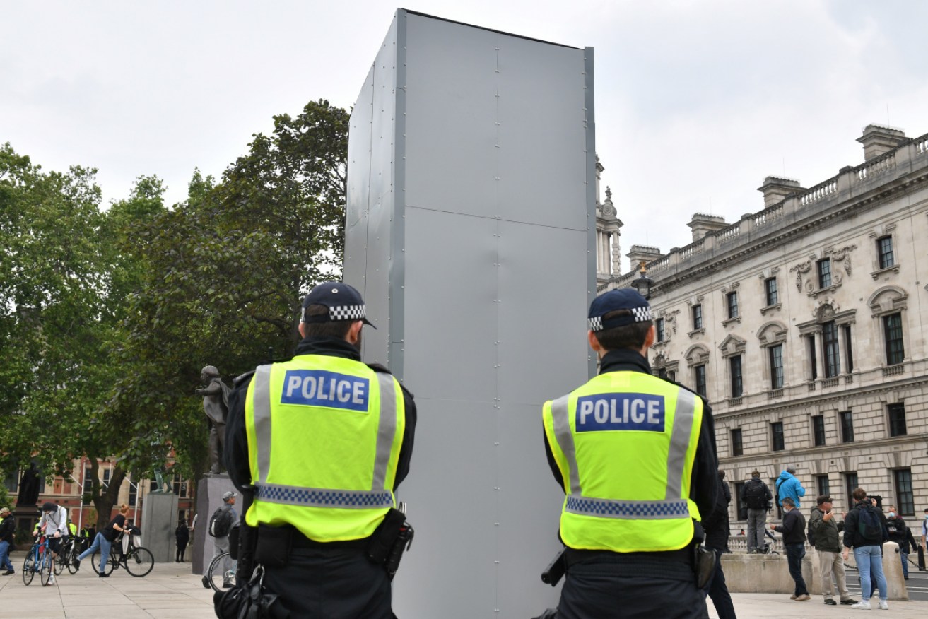 Police officers guard a boxed up statue of Sir Winston Churchill in Parliament Square, London, as people participate in a Black Lives Matter protest.