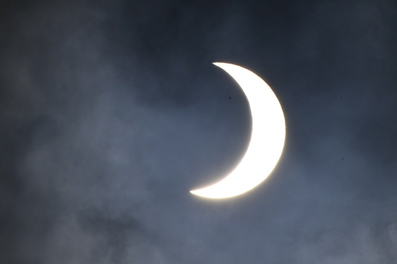 The sun shines amid the clouds as the moon partially covers it during the annular solar eclipse.