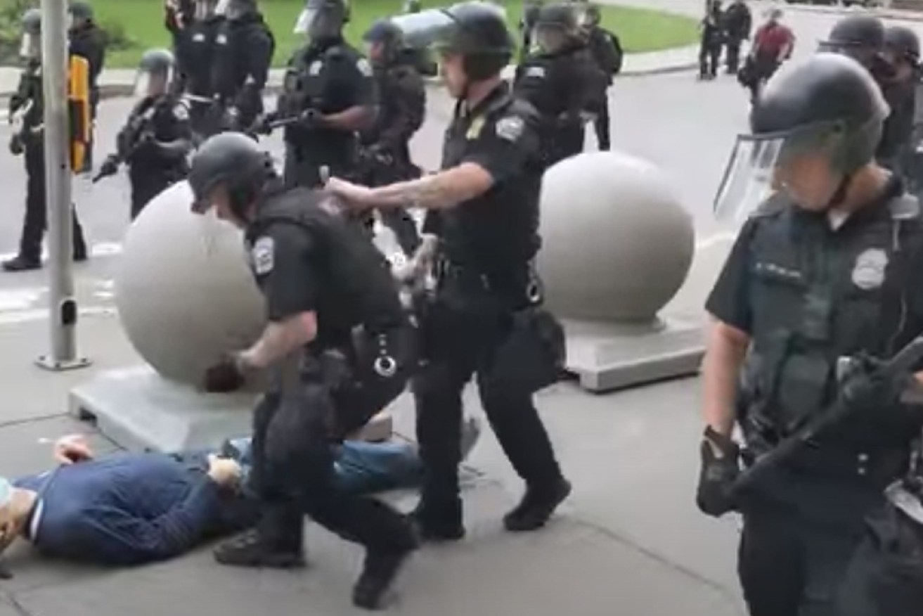 Police walk past Martin Gugino, while he lies on the ground.
