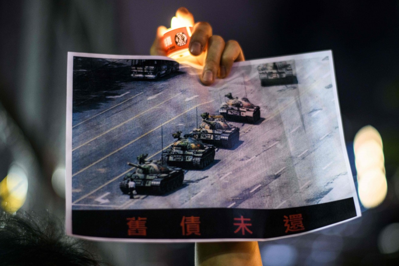 A Hong Kong protester holds a poster of the famous 'Tank Man' stopping the regime's armoured column before the killing began in earnest on June 4, 1989. <i>Photo: Getty</i>