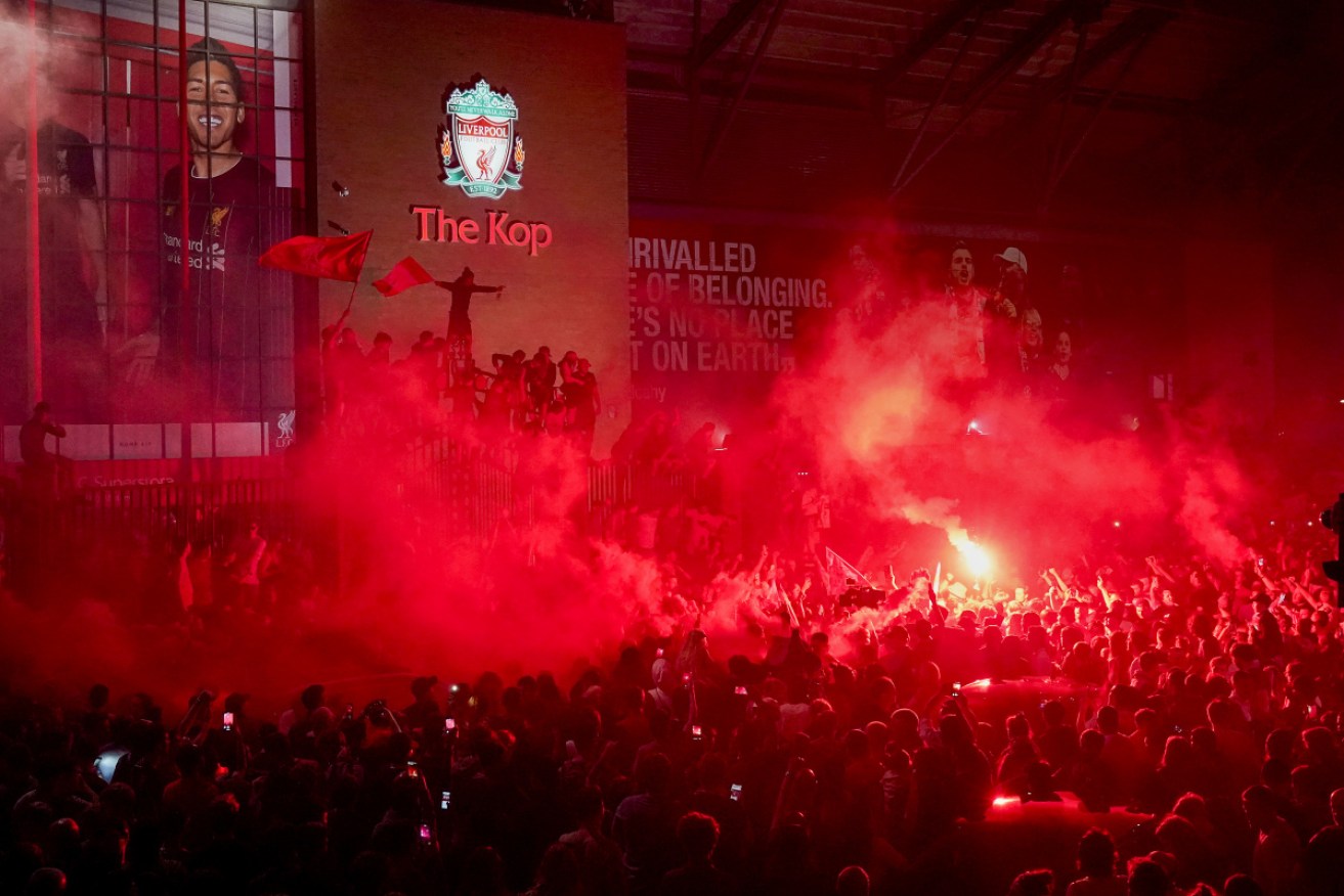 Liverpool fans light red flares as the celebrations unfold in earnest.