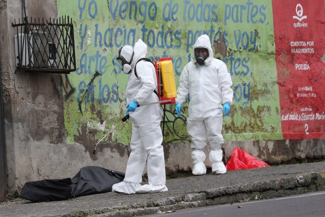 A forensic investigator disinfecting a body bag holding the remains of a man who collapsed on the street and died from from the coronavirus in Quito, Ecuador.