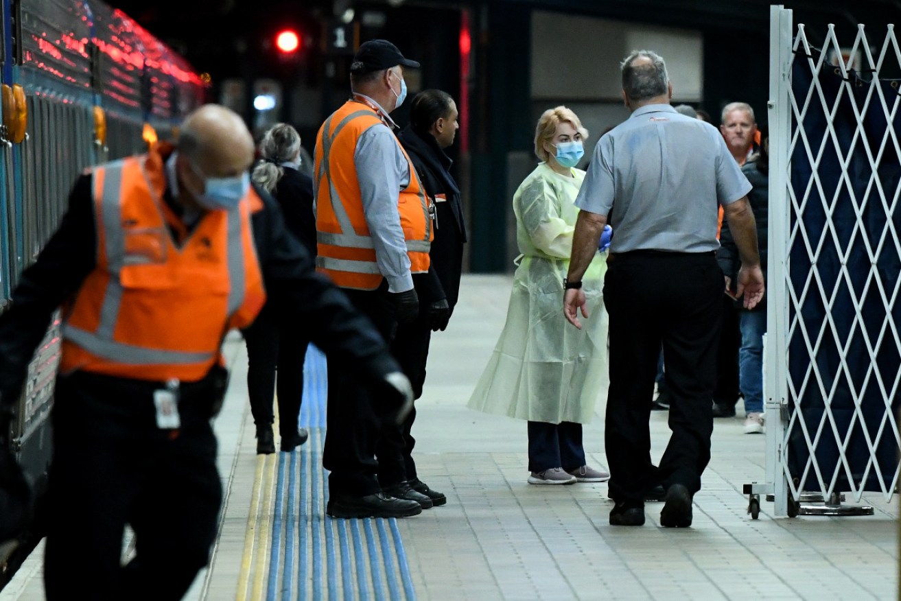 NSW Health officials  wait for travellers to disembark from Melbourne at Central Station in Sydney.