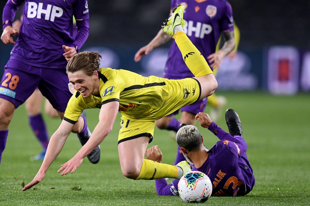 Wellington's Callum McCowatt is floored by the tackle of Perth's Osama Malik in Sydney on Wednesday.