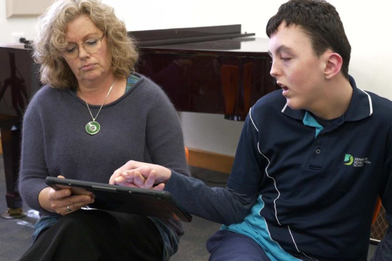 Tyler's education assistant Jayne Taylor helps him communicate.
