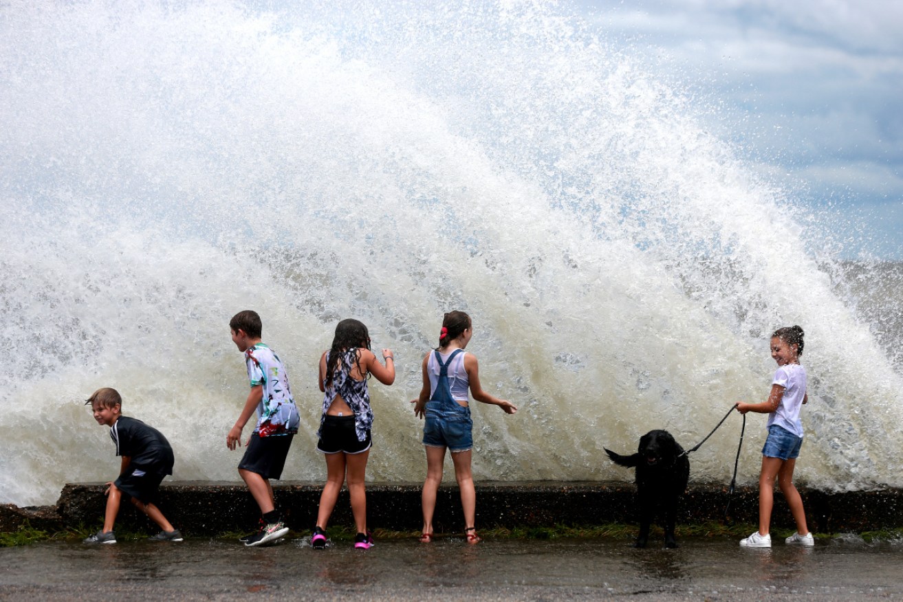 Kids play along the seawall as Tropical Storm Marco makes landfall along the Gulf Coast on in New Orleans, Louisiana. 