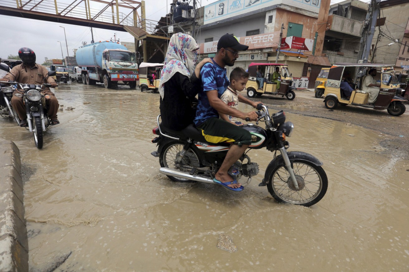 Motorcyclists ride through a flooded road in Karachi, Pakistan on Sunday.