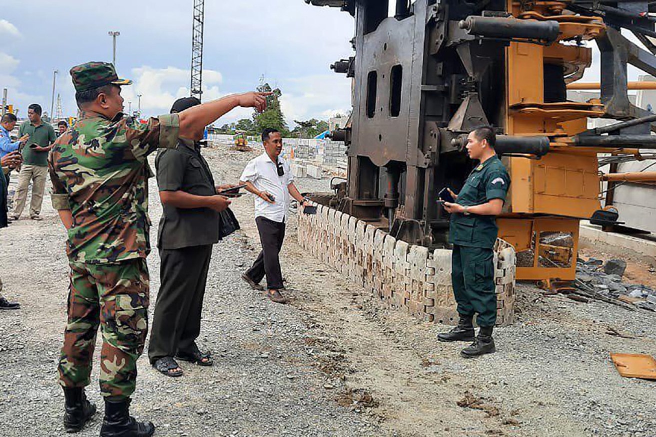 Officers stand by a collapsed crane at Poipet, west of Phnom Penh, on Wednesday. 