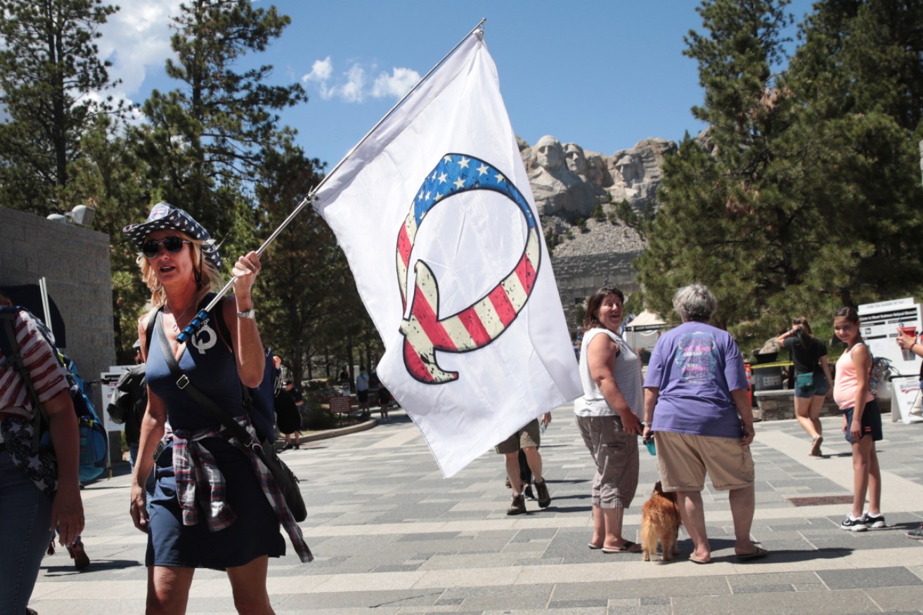 A Donald Trump supporter holding a QAnon flag visits Mount Rushmore National Monument in July.