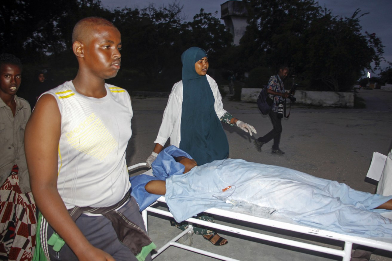 Medical workers and other Somalis help a civilian woman, who was wounded when a powerful car bomb blew off the security gates to the Elite Hotel.
