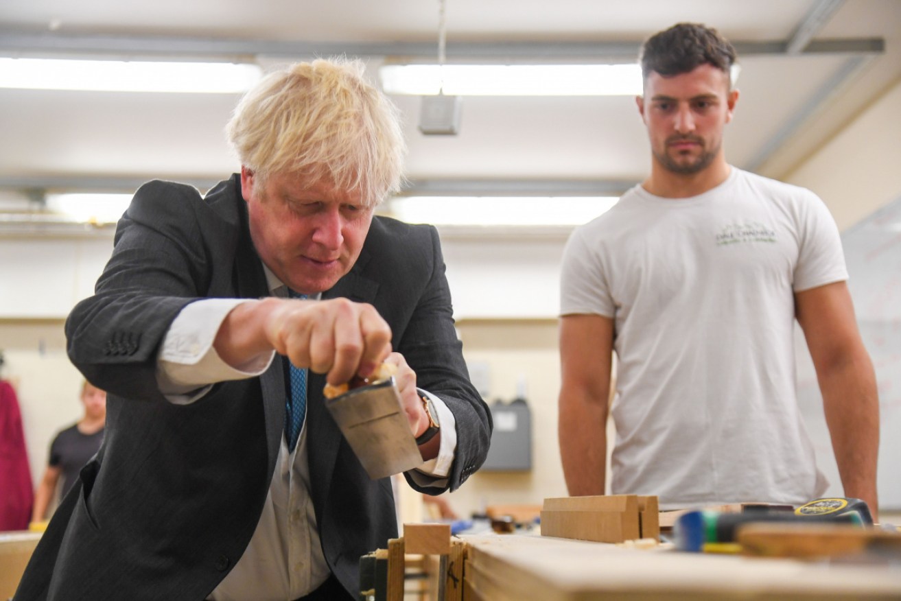 Boris Johnson gets to grips with a planer on a trip to a technical college in Exeter on Tuesday.