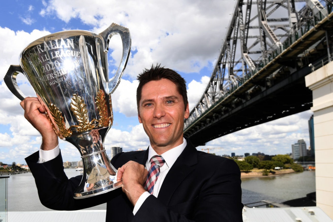 Former Brisbane Lions player Simon Black with the AFL Premiership cup in Brisbane ahead of a month of festivities. 

