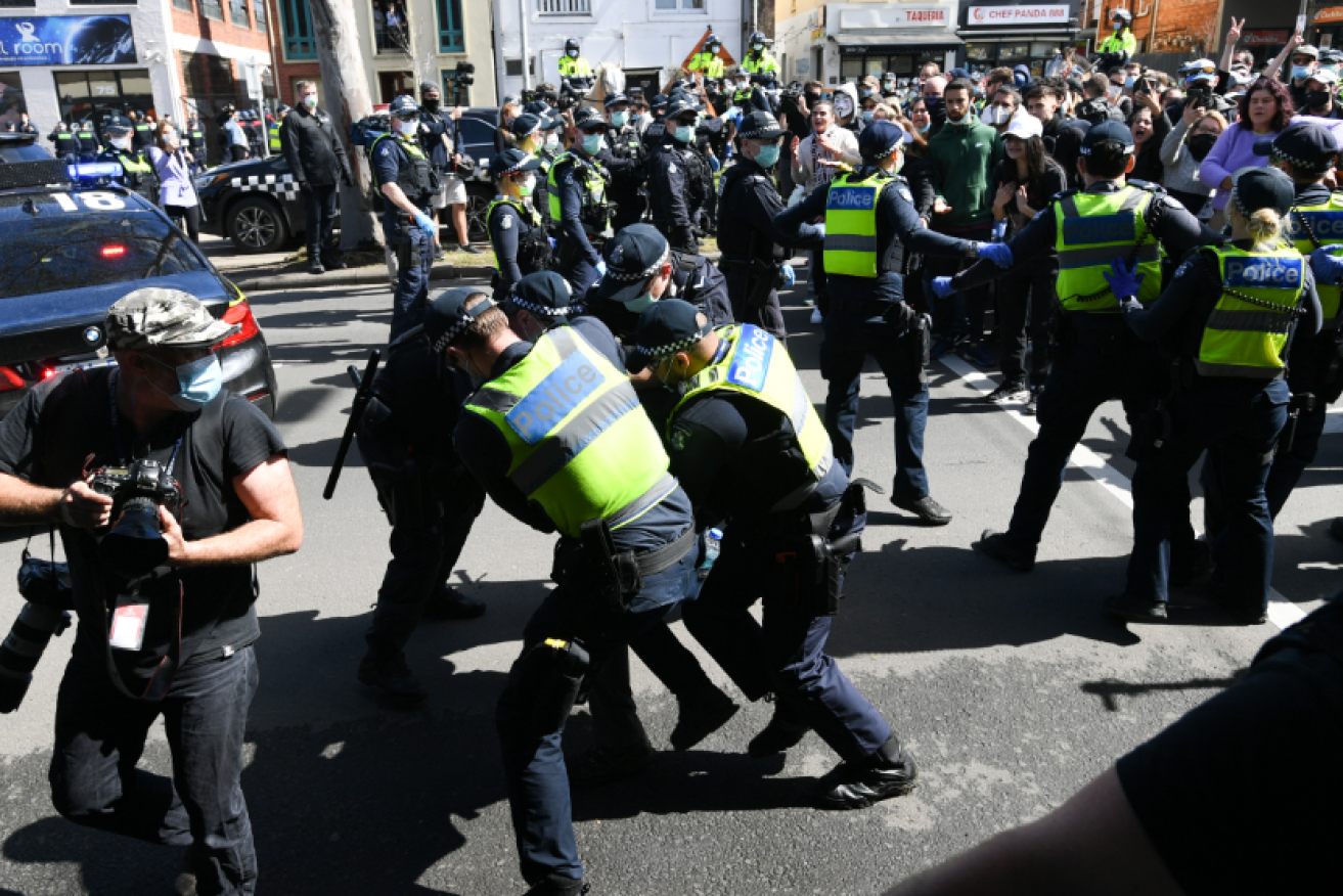Police gang tackle a demonstrator amid wild scenes at the Victoria Market.
