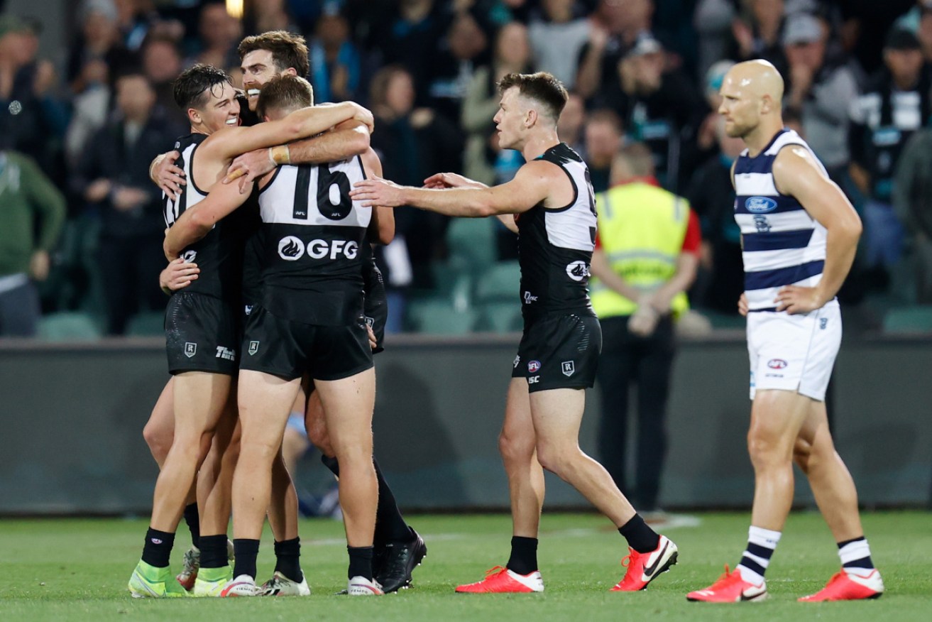 Power players celebrate as Geelong's Gary Ablett looks on.