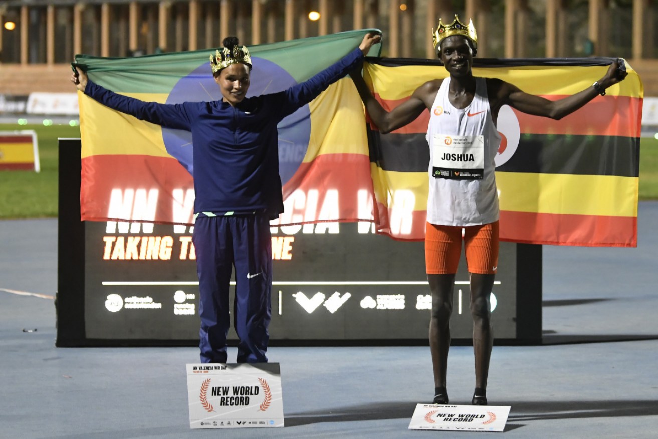 Ethiopian Letesenbet Gidey, left, and Ugandan Joshua Cheptegei pose after breaking the 5,000m and 10,000m track world records.