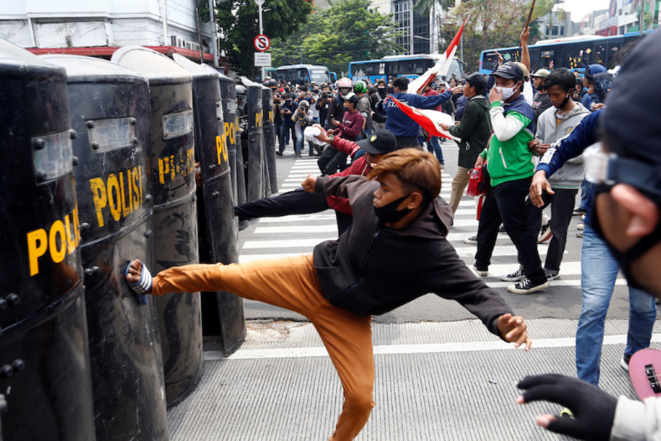 A protester throws himself against a wall of police shields in Jakarta.