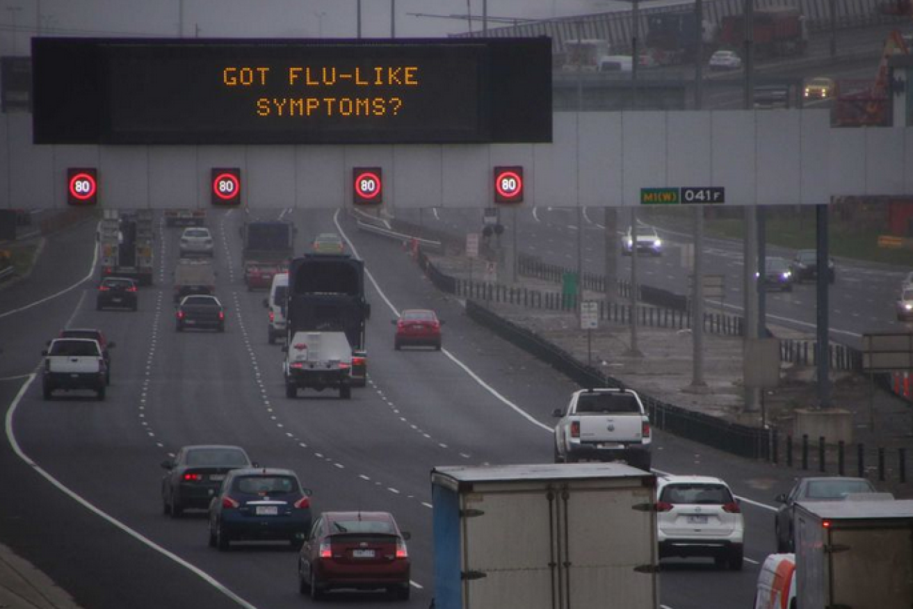 Sign of the times: Through the gloom of a grey Melbourne morning a freeway sign reminds drivers that the COVID crisis is far from over.
