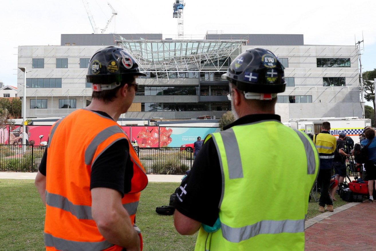 Construction workers examine the scene of a collapsed building at Curtin University in Perth on Tuesday.