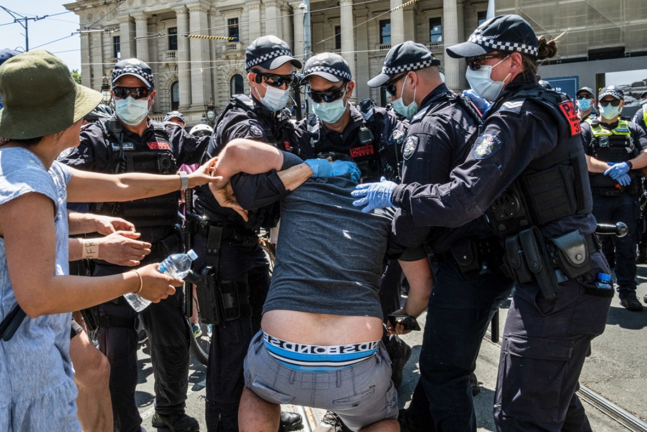 A protester is arrested after clashing with the Police at Parliament House in Melbourne on Tuesday.