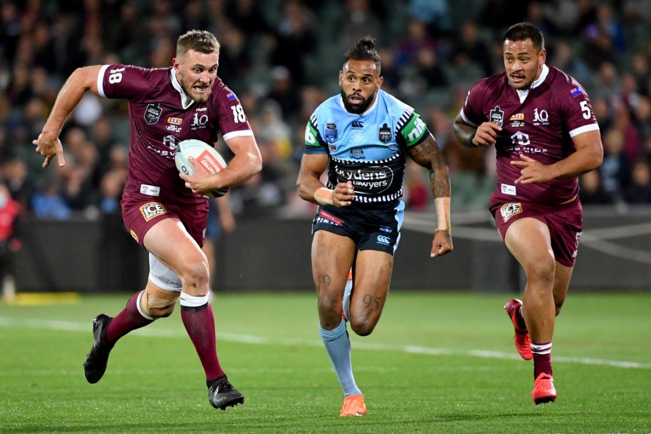 Kurt Capewell (left) of the Maroons makes a break past Josh Addo-Carr (centre) of the Blues during Game 1 of the 2020 State of Origin series on Wednesday night.
