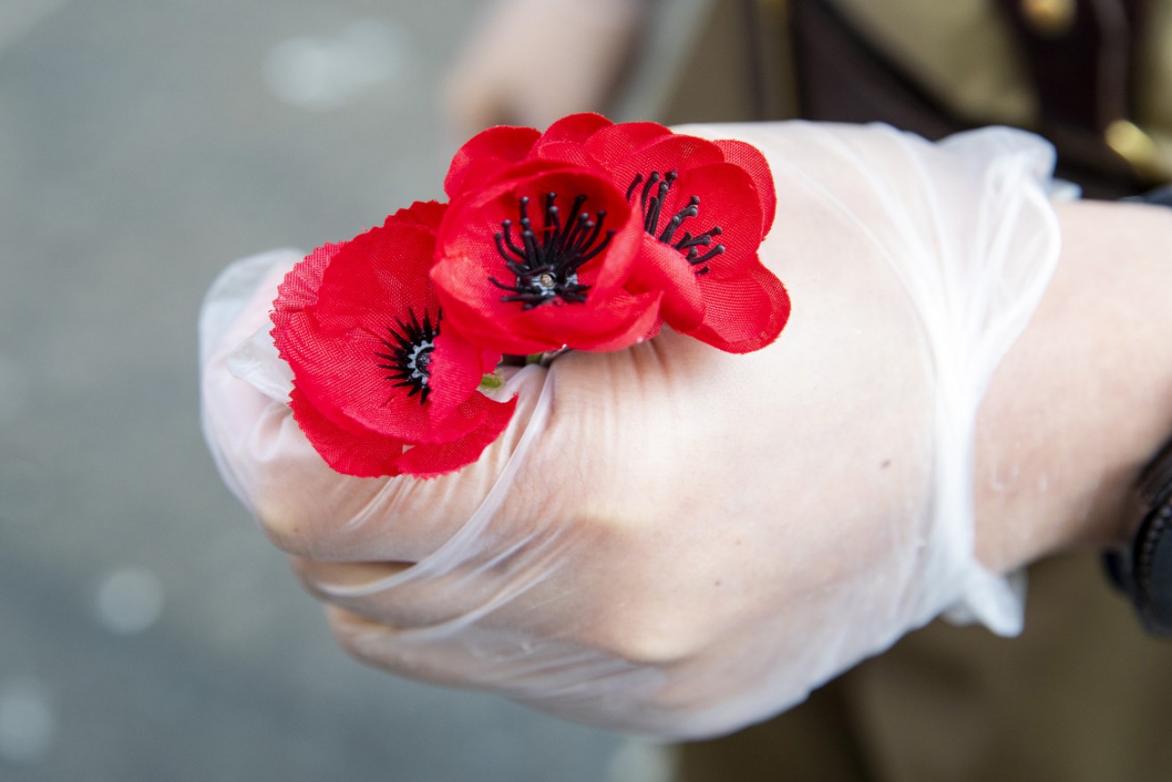 A gloved hand is seen holding poppies at the invite-only official Remembrance Day service in Martin Place on November 11, 2020. 