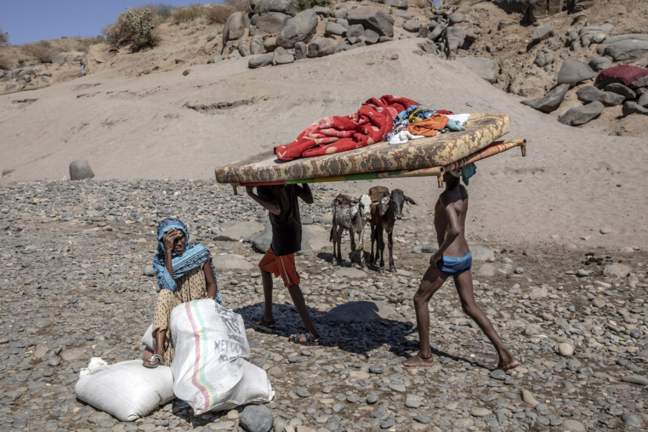 Tigray refugees who fled the conflict carry their furniture on the banks of the Tekeze River on the Sudan border at Hamdayet.