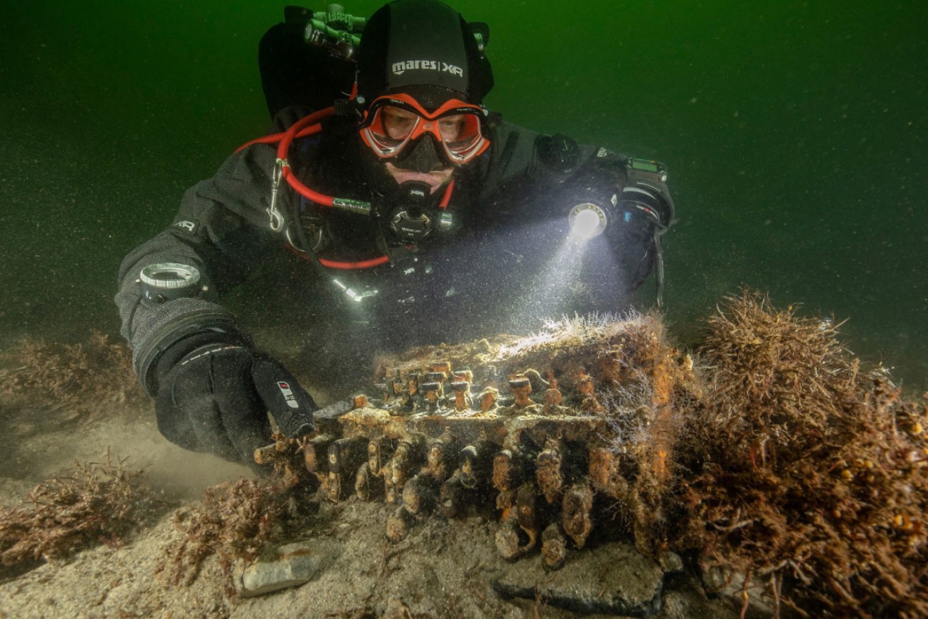 Underwater archaeologist Florian Huber examines the Enigma machine where it was found.