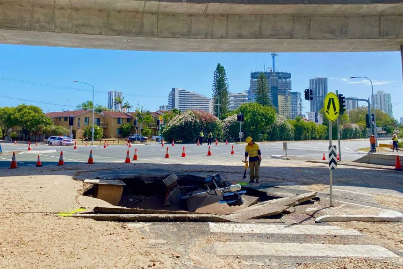 A large sinkhole has swallowed traffic lights on a busy intersection near Pacific Fair Shopping Centre on the Gold Coast.